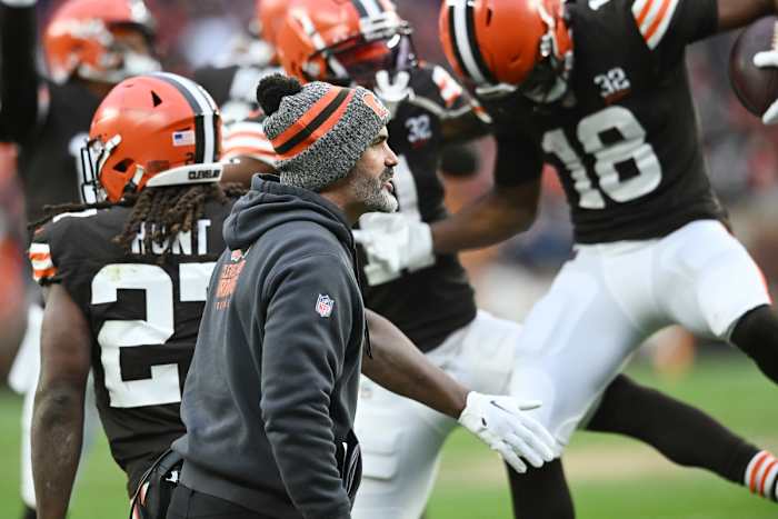Kevin Stefanski walks as Browns players jump up behind him